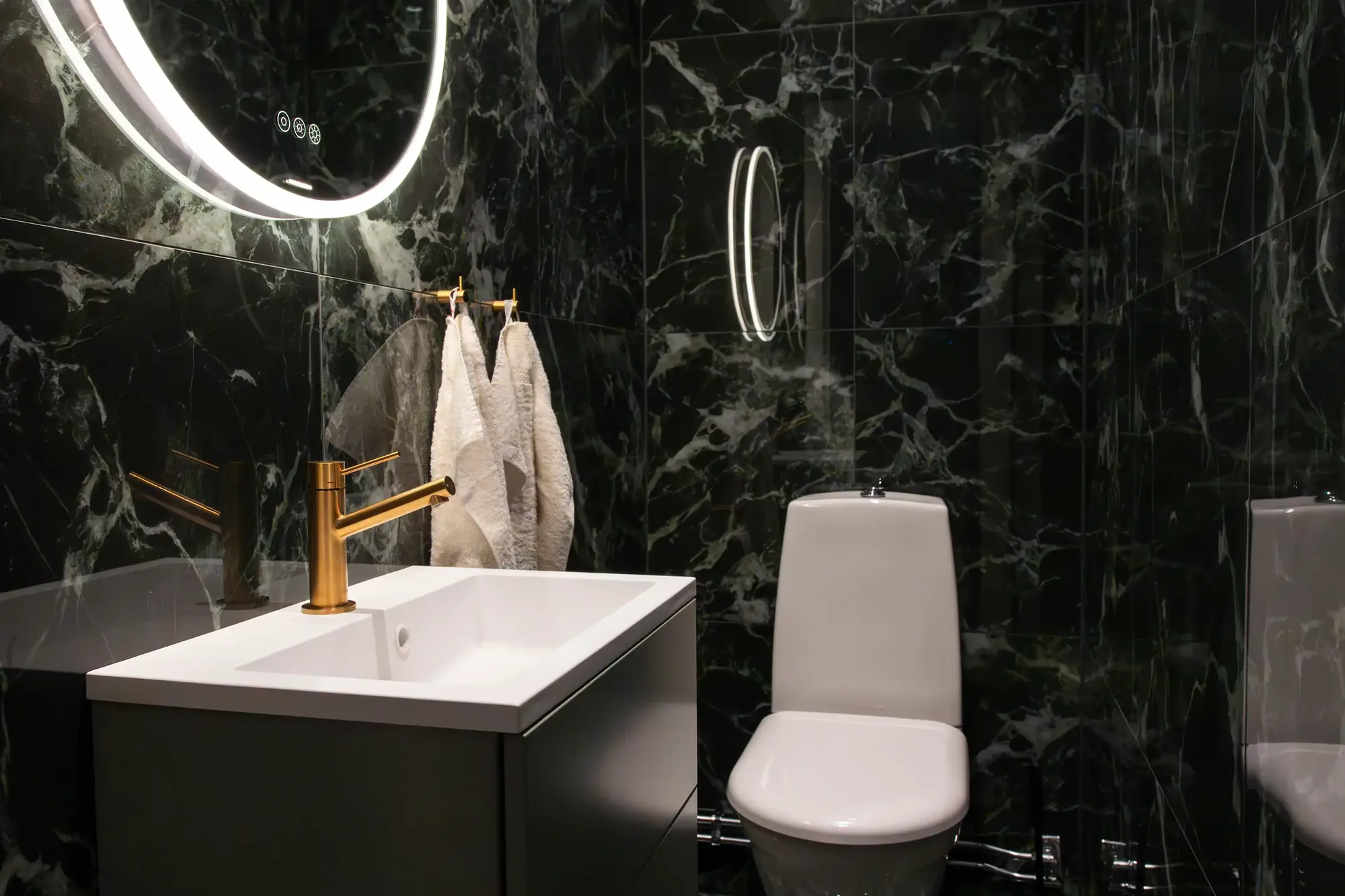 badrumsrenovering efter-bild med wc, grönt kakel, spegel och kran i mässing