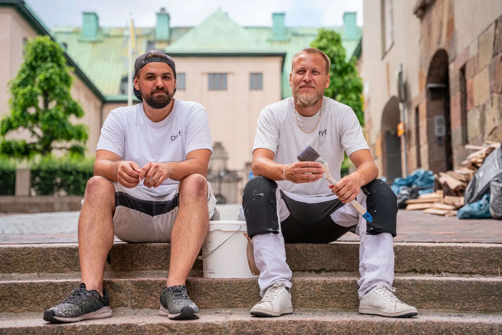 Två målare med pensel på trappa